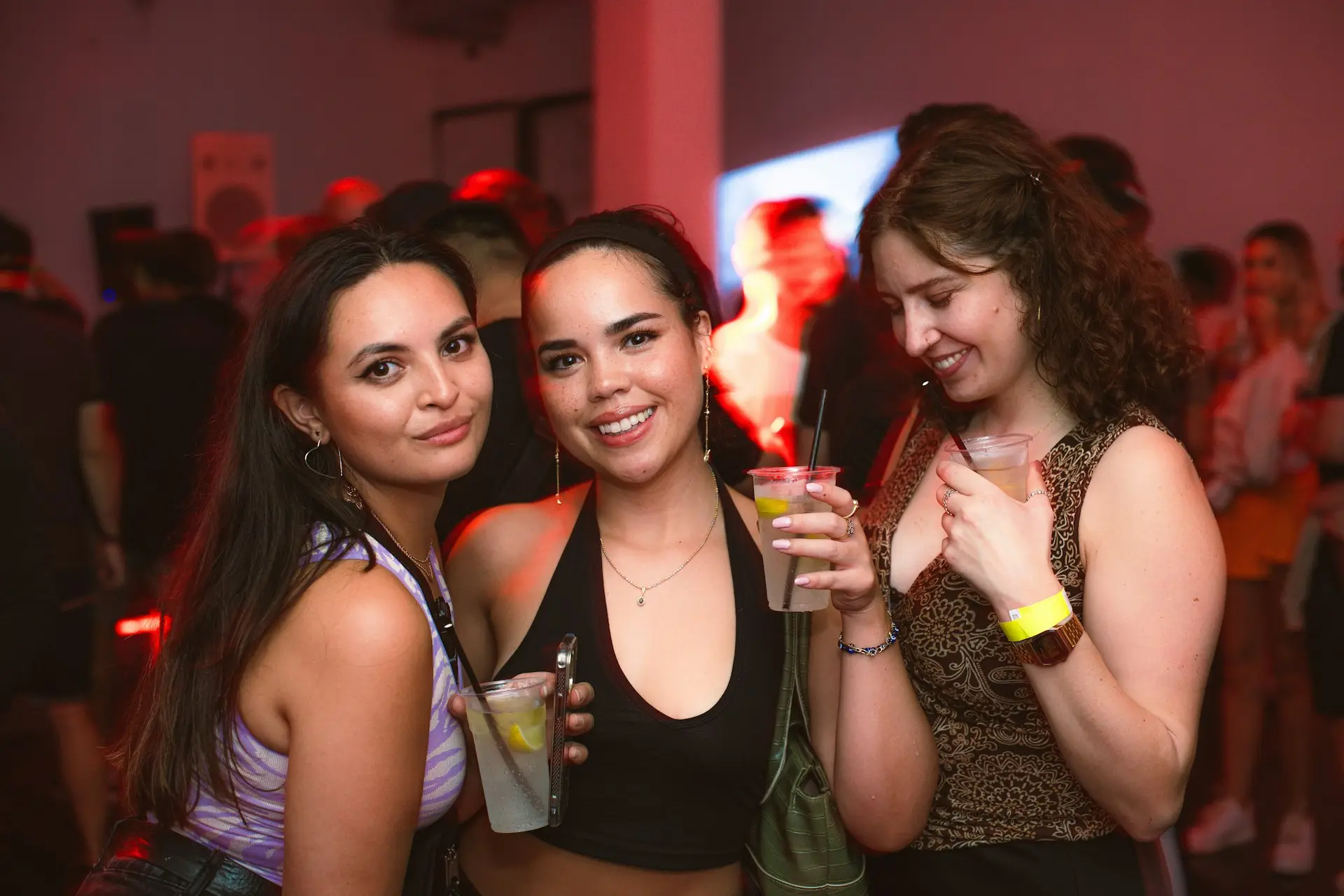 a group of women standing next to each other holding drinks